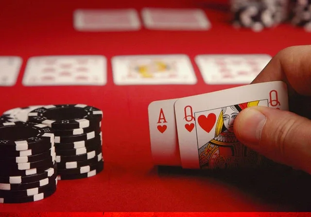Suited Hand Ace and Qeen of hearts on a poker table next to chips